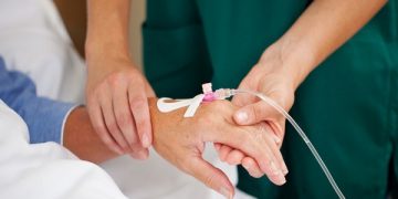 Female doctor checking patients pulse in hospital