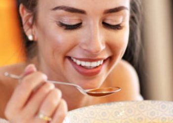 Picture of adult woman tasting pumpkin soup in the kitchen