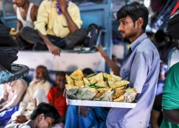 A vendor sells fried snacks on a train in northern India. Food vendors are a regular presence on most trains, jumping on and off trains at various stations, offering passengers a welcome snack break during their long journeys