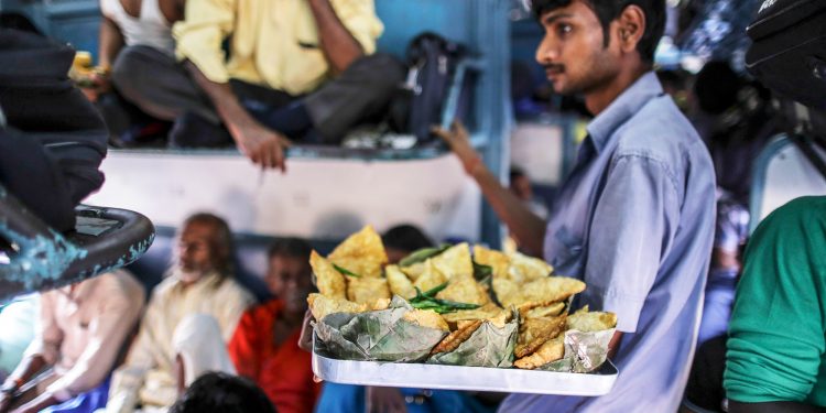 A vendor sells fried snacks on a train in northern India. Food vendors are a regular presence on most trains, jumping on and off trains at various stations, offering passengers a welcome snack break during their long journeys