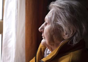 portrait of sad lonely pensive old senior woman looking in a window
