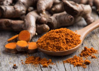 pile of fresh turmeric roots on wooden table