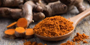 pile of fresh turmeric roots on wooden table