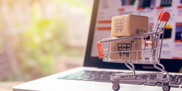 Shopping online concept - Parcel or Paper cartons with a shopping cart logo in a trolley on a laptop keyboard. Shopping service on The online web. offers home delivery.