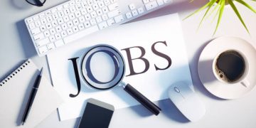 Top view of a white desktop with magnifying glass over the word JOB