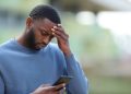 Concerned black man reading bad news on phone